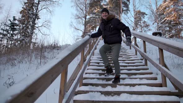 Young Male Throwing Snow From Stairs Railing Into Camera