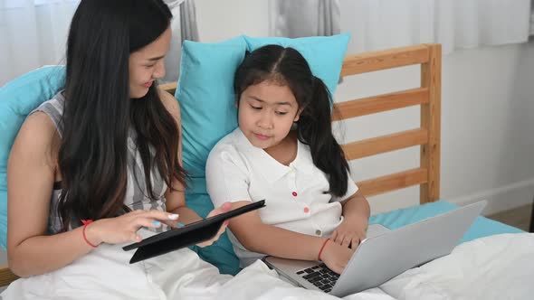 Two sisters relaxing in the bedroom And watch tablet and laptop at home, sisters family