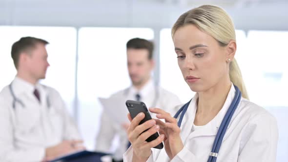 Portrait of Serious Female Doctor Using Smartphone in Office