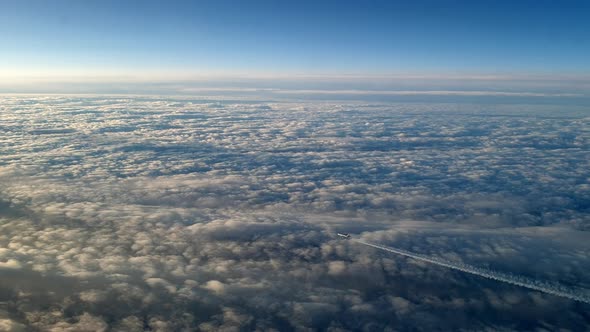 Incredible view from the cockpit of an airplane flying high above the clouds leaving a long white co