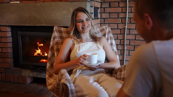 Young Beautiful Woman Smiling Sitting on Rocking Chair Talking with Unrecognizable Man