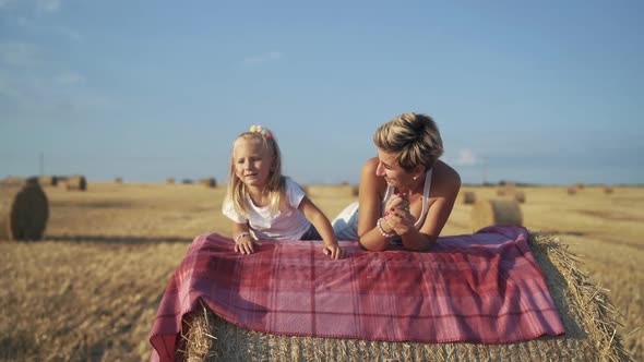 Happy Family Having Relax on a Haycock on a Sunny Day in Field