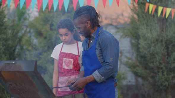 Charming Teenage African American Girl Walking to Man Cooking Bbq Grill