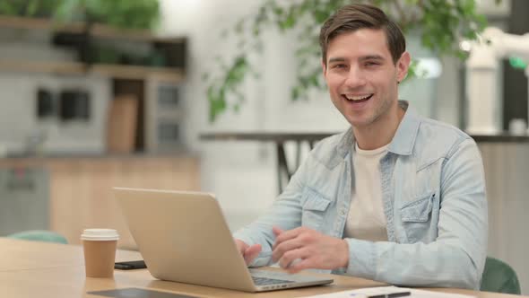 Thumbs Up By Creative Young Man with Laptop at Work