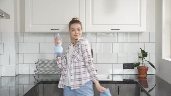 Happy Housekeeper Enjoys the Cleaning Process Dancing in Kitchen with Detergents in Her Hands