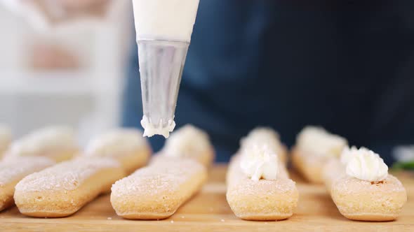 Lady Arms in Uniform Adding Shake Up Icing on Fresh Biscuit Cakes Closeup