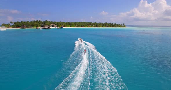 Aerial drone view of a man water skiing near a tropical island.