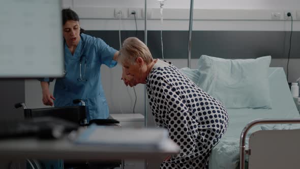 Nurse Giving Assistance to Aged Woman in Hospital Ward