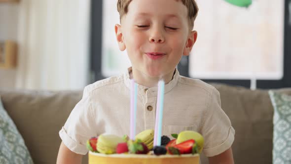 Happy Little Boy Blowing Candles on Birthday Cake