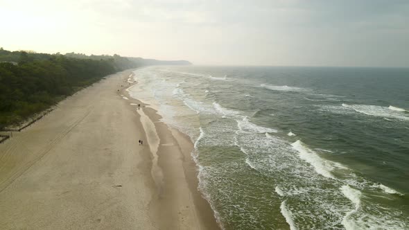 Aerial Pull Back over Baltic Sea Beach in Poland with Green Waves