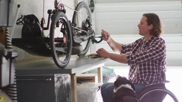 Focused caucasian disabled man in wheelchair repairing bike in garage