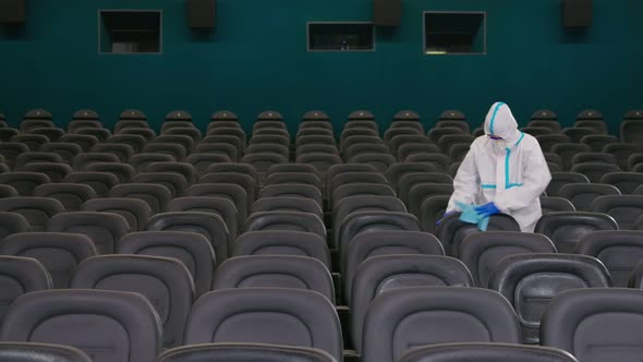 Worker Wiping Chairs with Disinfectants in Cinema