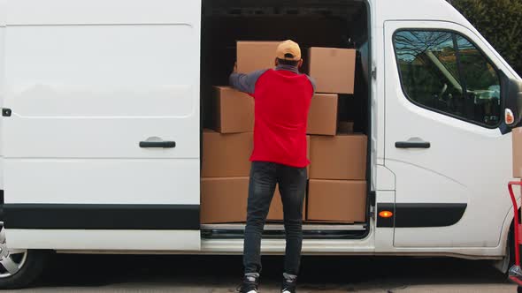 Delivery Man with Face Mask Putting Parcel Into the Van