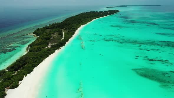 Wide angle overhead tourism shot of a white paradise beach and aqua blue water background in colorfu