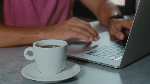 Cup of coffee on background of business man working with laptop in cafe