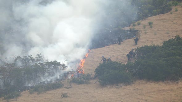 Wildfire burning on mountain as firefighters control the blaze