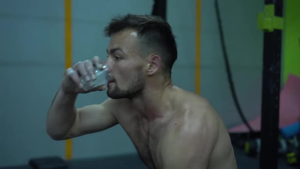 Portrait Professional Muscular Athletic Man Bodybuilder Drinking a Water the in Gym. Perfect Body