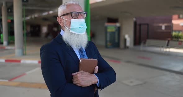 Senior business man holding digital tablet in the city while wearing safety face mask