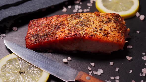 Delicious Baked Golden Salmon on a Black Plate in the Kitchen
