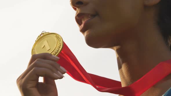 Happy mixed-race sportswoman smiling and rejoicing victory and gold medal