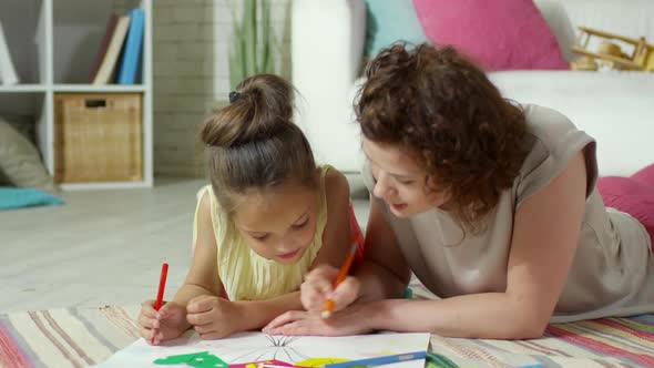 Mother and Daughter Lying on Floor and Drawing Picture alt