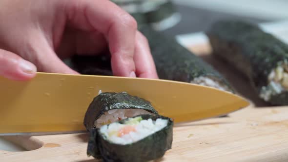 The Chef Cuts Sushi and Rolls Made From Seafood with Asian Ingredients with a Knife