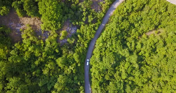 Aerial drone view of a minivan car vehicle driving on a rural road