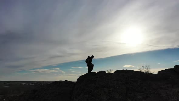 Silhouette of a Man Walking Along a Ridge