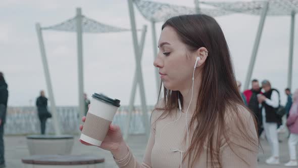 Slow Motion of Happy Young Woman in Headphones Sitting Outdoors in City Having Fun Alone