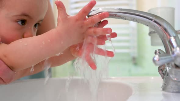 parent is teaching her son how to wash hands.