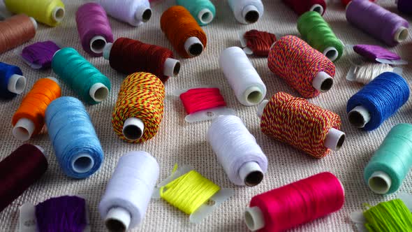 A top view of colorful mouline threads and multicolored spools isolated on a burlap background.