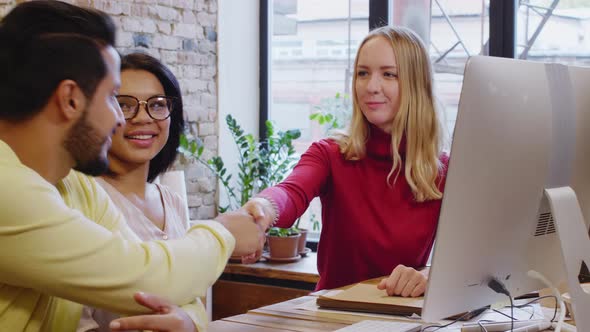 Cheerful Female Designer Giving Handshake to Clients 