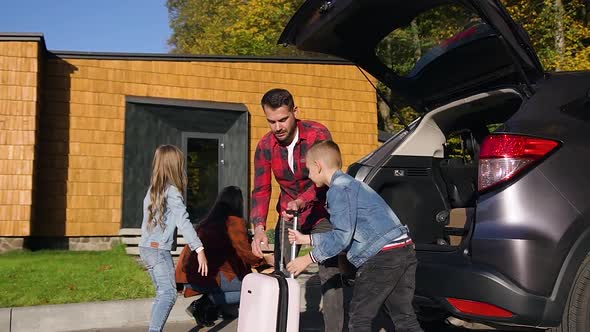 Joyful Pleasant Family Which Loading their Suitcases Into Trunk Before Joint Car Trip