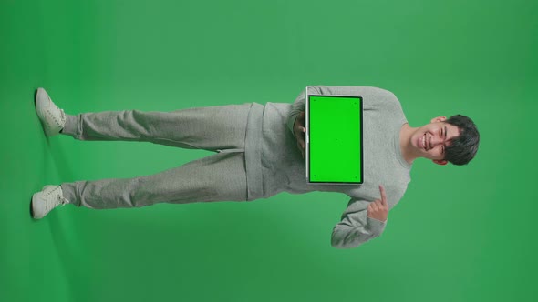 Full Body Of Smiling Asian Man Holding And Pointing Green Screen Computer On Green Screen