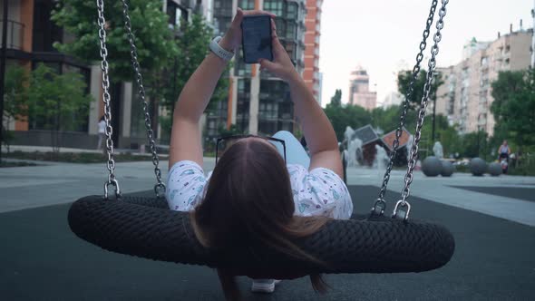 Girl with Dark Hair is Slowly Rolling on a Swing Relaxed Rest