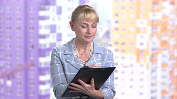 Smiling Mature Woman Writing on Clipboard.