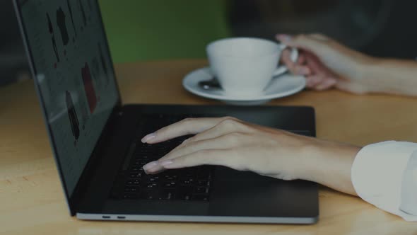 Woman Hand Typing on Computer at Wooden Desk and Hold Cup of Coffee