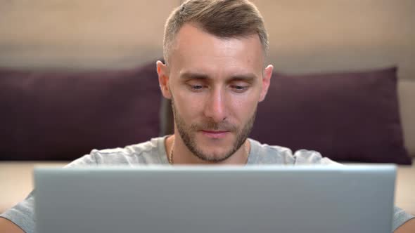 Close-up, a man looking at a laptop screen while sitting in front of the camera