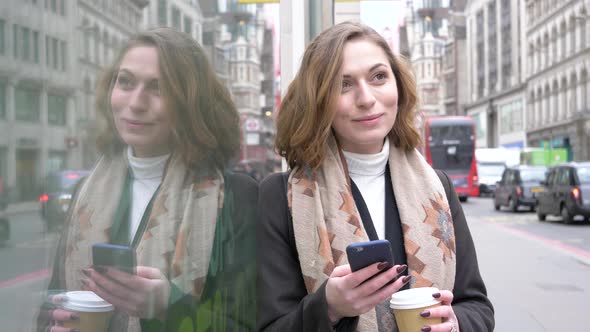Blond woman using smartphone with coffee to go in London