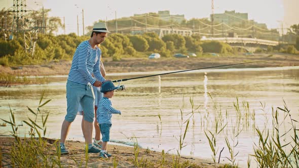 Family on Fishing - Father Holding a Fishing Rod and Showing How To Fishing To His Little Son