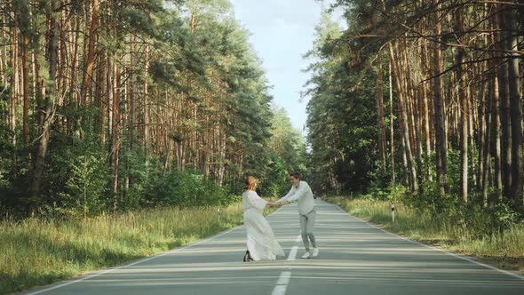 A Cheerful Young European Couple is Walking in a Picturesque Place in the Pine Forest with Soft