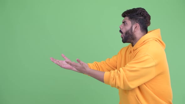 Happy Young Overweight Bearded Indian Man Showing Something and Looking Surprised