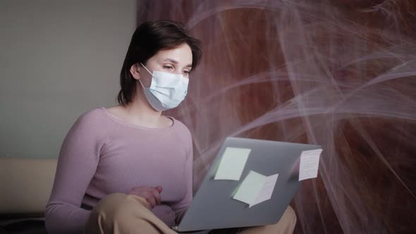 Woman at Home in Medical Mask Sit on the Bed in Front of Laptop Look at Pc Screen Chatting with