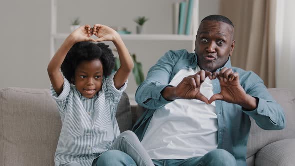 Happy Funny African American Family Mature Father and Little Daughter Sitting on Sofa in Room