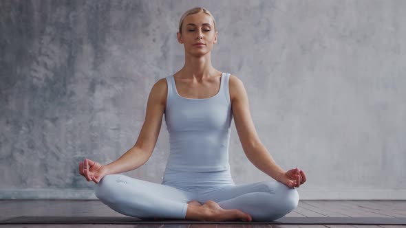 Young and sporty girl in sportswear is doing yoga exercises in home interior.