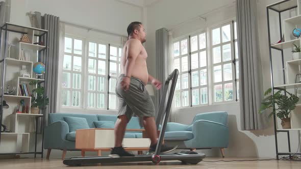 Asian Fat Man Wearing No T-Shirt Training On Walking Treadmill At Home
