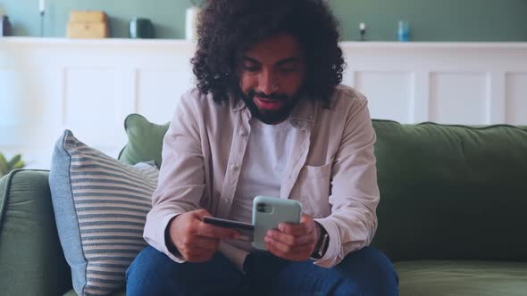 Young Arabian Man Do Shopping in Mobile Phone Pays for Purchase with Bank Card