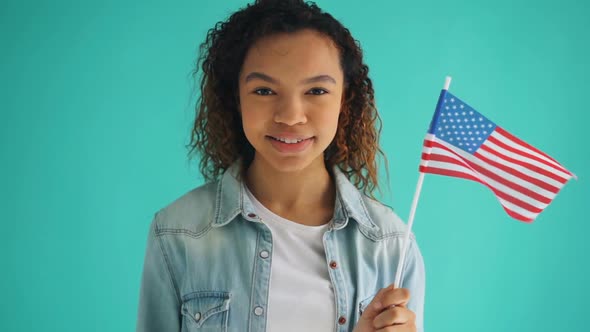 Slow Motion of Mixed Race Girl Holding American Flag Smiling on Blue Background