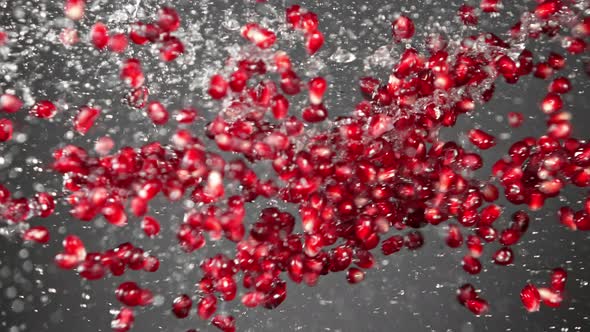 Super Slow Motion Shot of Fresh Pomegranate Seeds and Water Side Collision on Grey at 1000Fps.