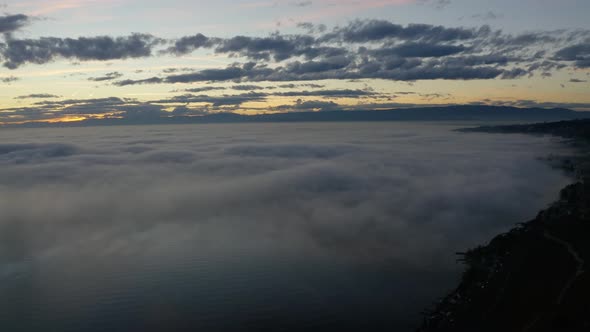 Aerial panning over fog covering lake Léman at sunset.Villette, Lavaux - Switzerland